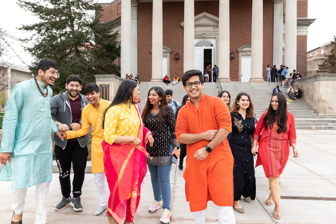 Photo of several international students laughing and smiling in front of Hendricks Chapel.