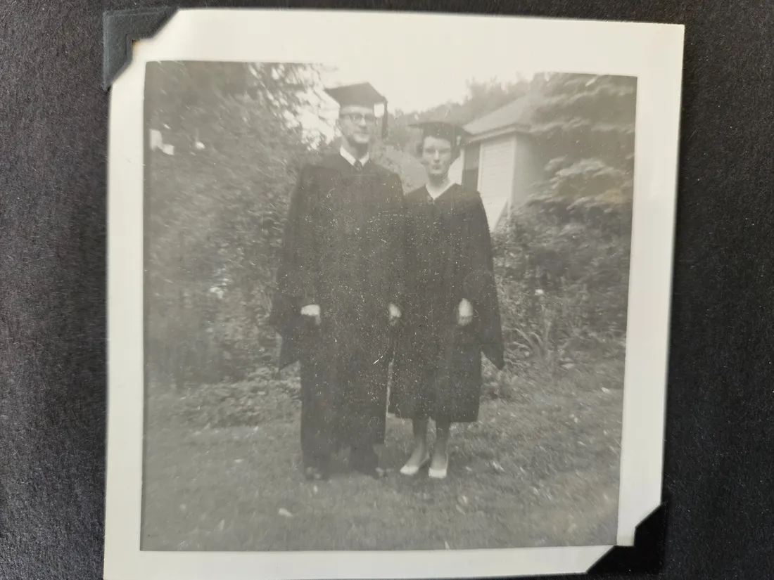 An old picture of two graduates in their cap and gown.