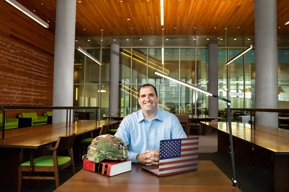 Ryan Marquette sits at table with laptop and textbooks in Dineen Hall