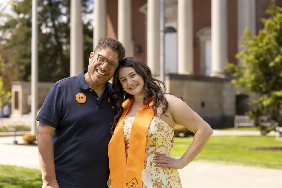 Mitch Messinger standing and smiling with daughter Sarah Jacoby, who is wearing an orange graduation stole.