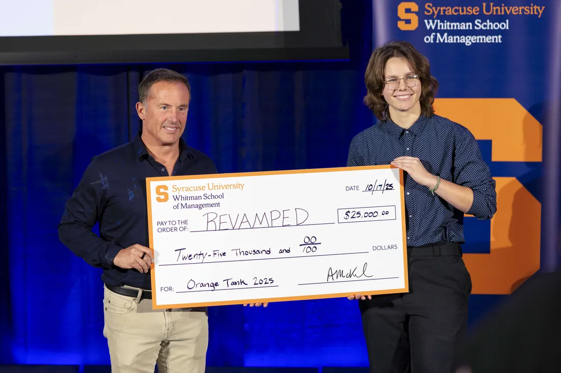 A student and judge holding a check at the Orange Tank competition.