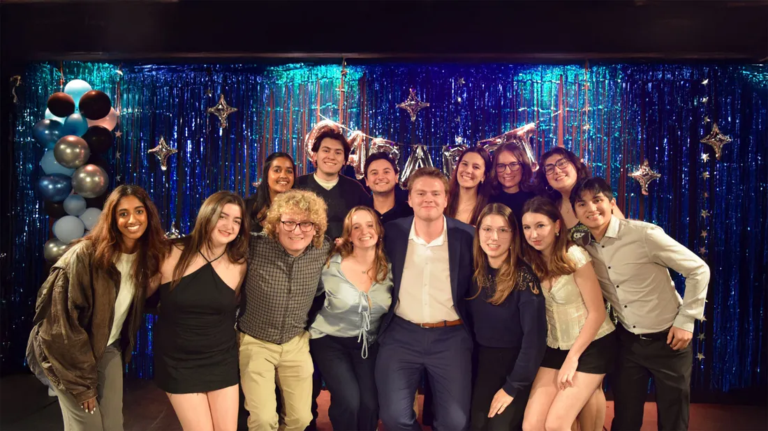 Group of students standing and smiling in front of a blue backdrop.