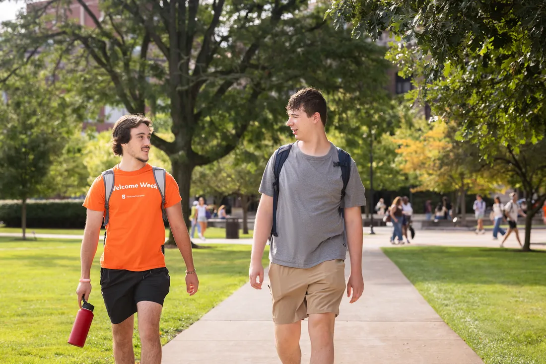 Two students are looking at a computer screen. One student is holding the mouse, while the other student is looking at the screen.
