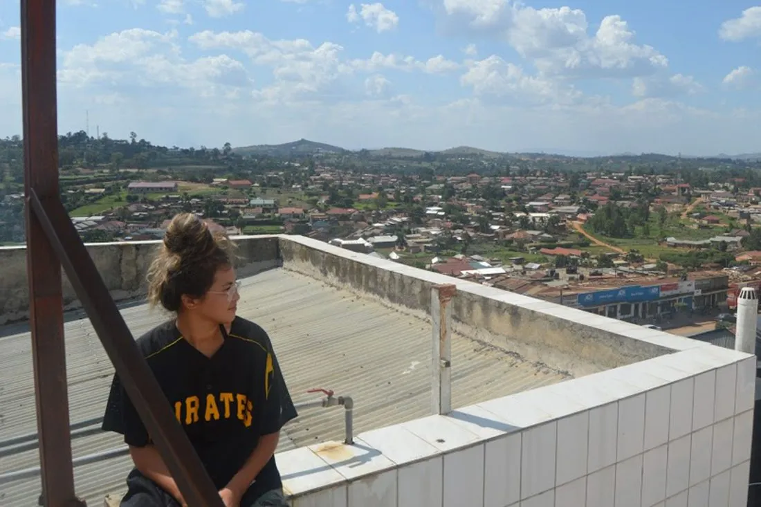 Shaylah Nichols on a rooftop with Uganda scenery behind her.