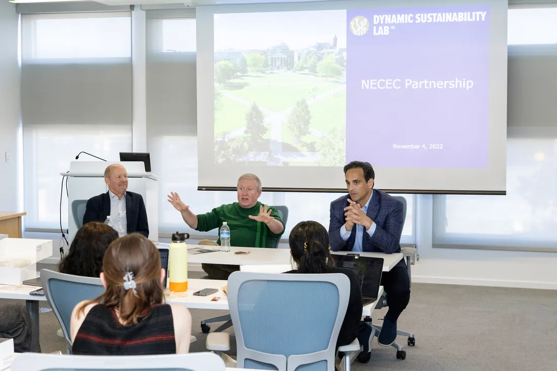 Three people sitting at a table and speaking to a room of people.