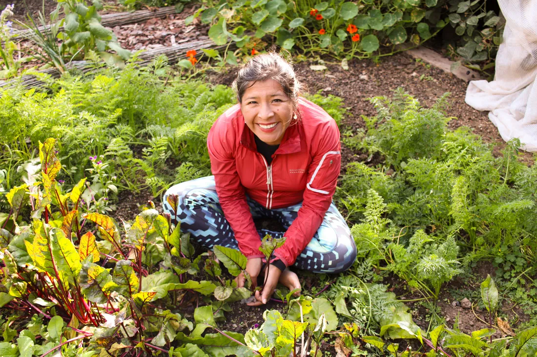 Person sittin in a garden while looking up at the camera.