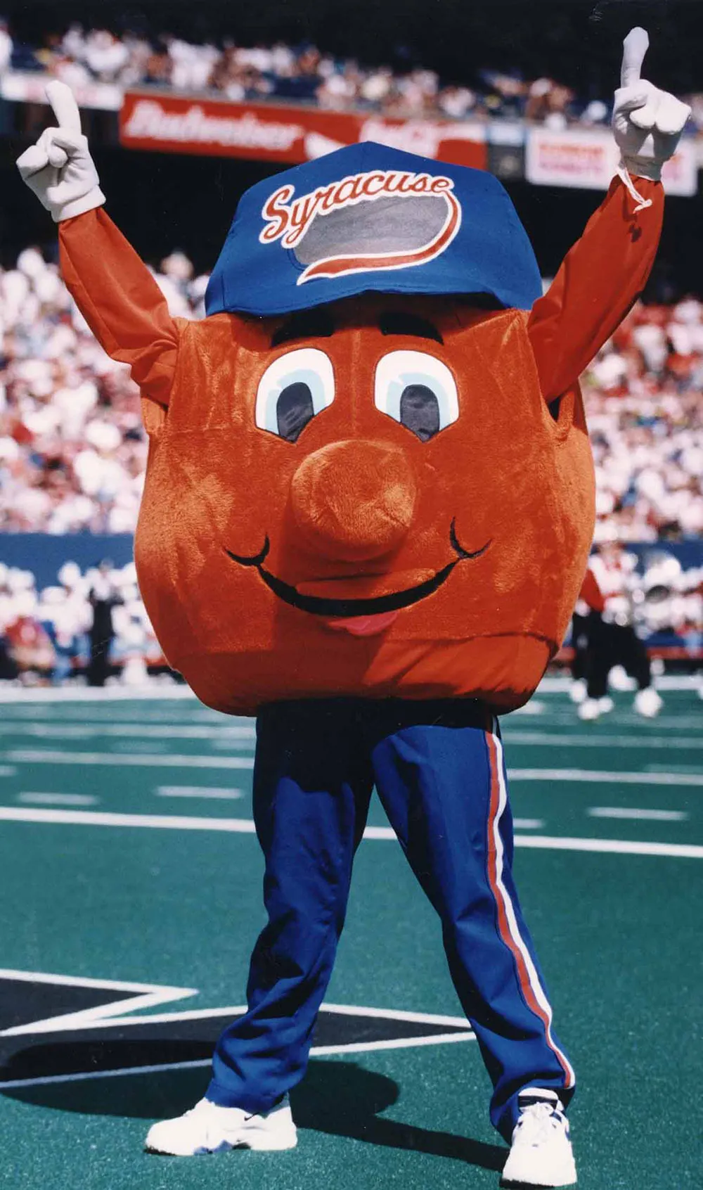 Vintage Otto the orange mascot cheering inside of stadium.