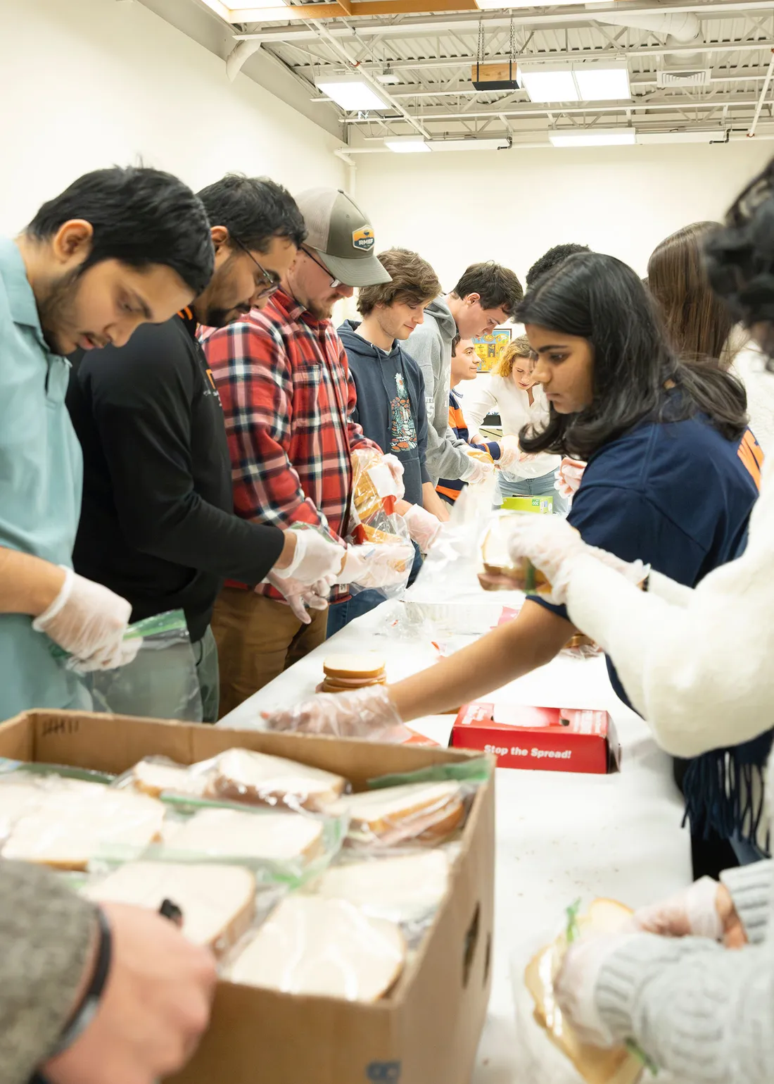 A group of Syracuse University students making sandwiches at a table as a part of Slice of Hope's Sandwich Making event.