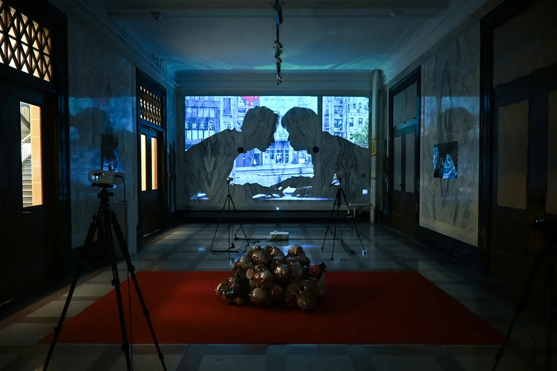 Darkened room with image of two people facing each other projected on wall.