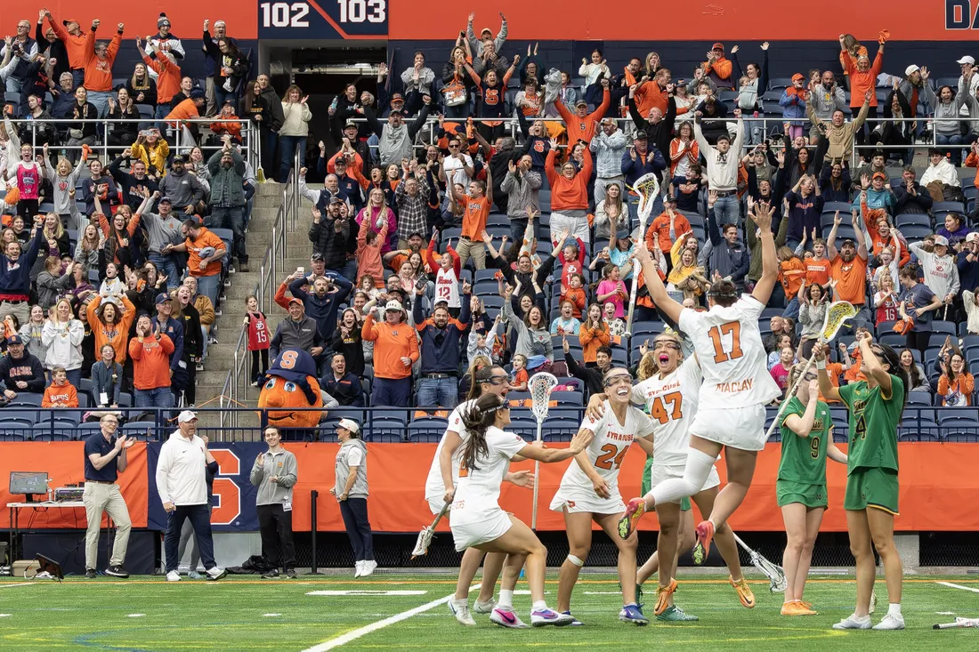 Members of the Syracuse University women's lacrosse team and crowd celebrating a win against Notre Dame.