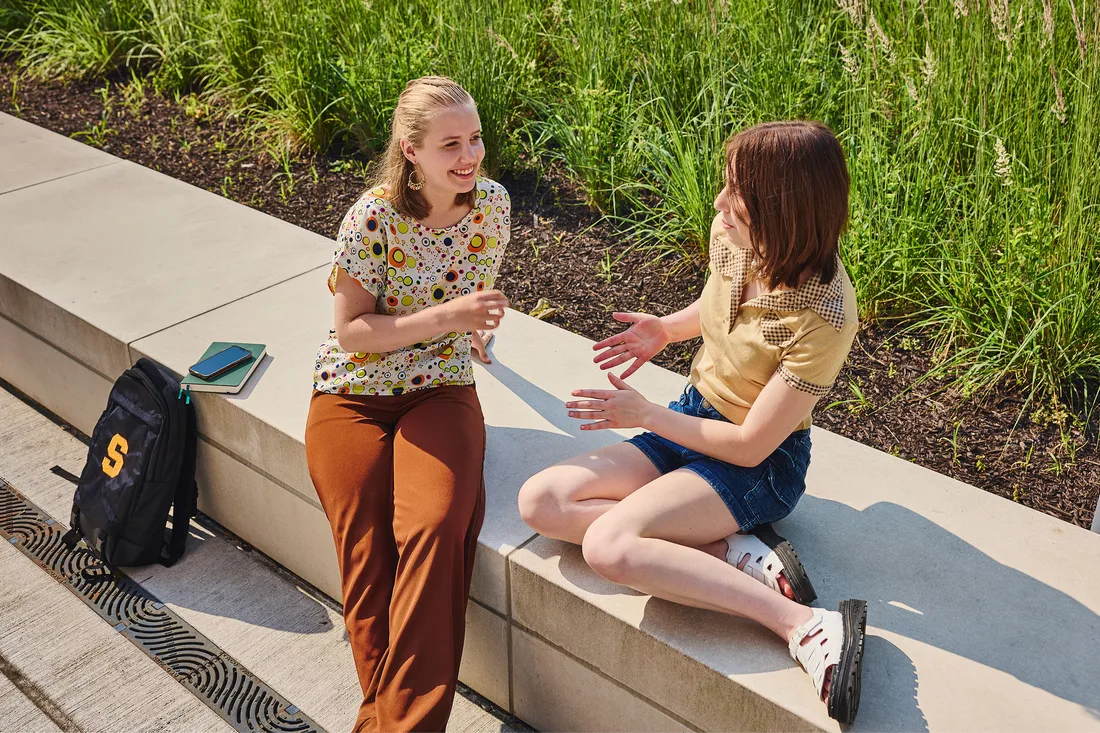 Two students sitting together and talking.