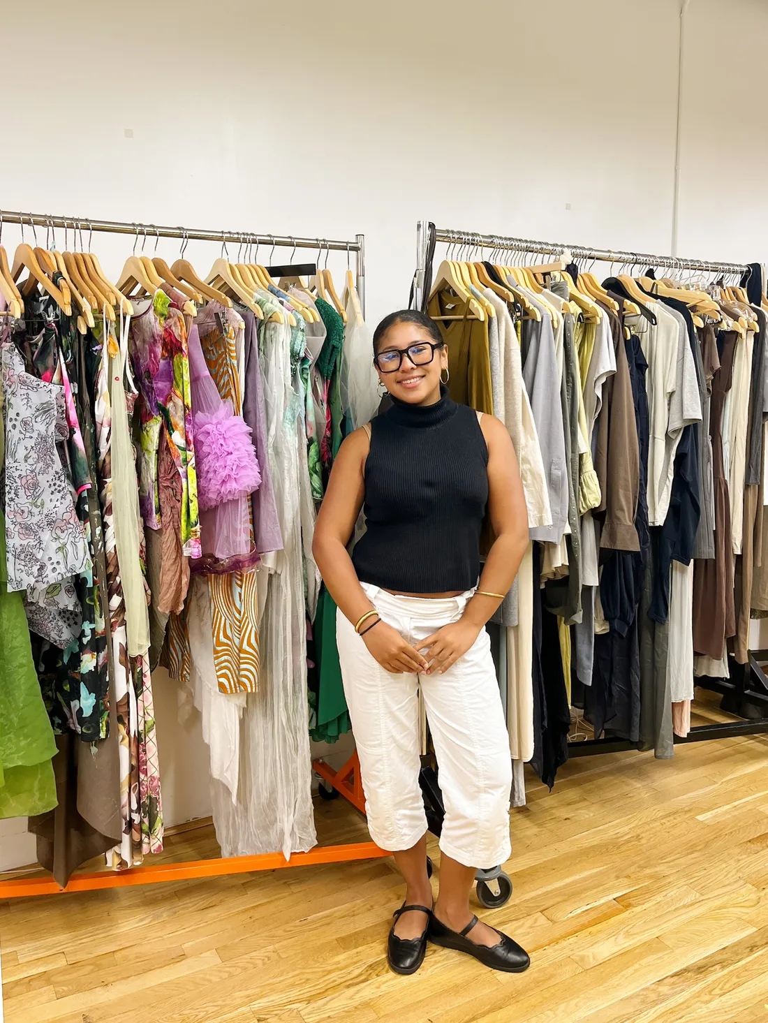 Person standing in front of racks of clothes.
