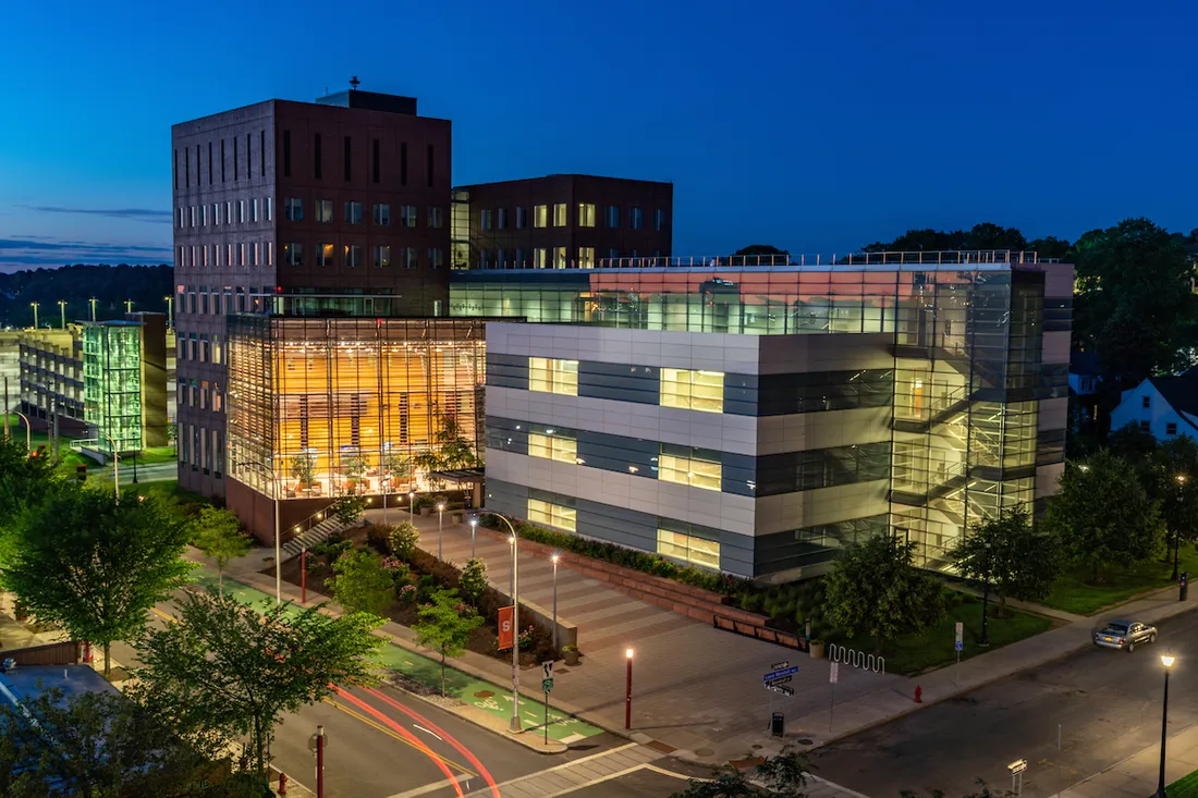 The exterior of the Whitman School of Management building at night.