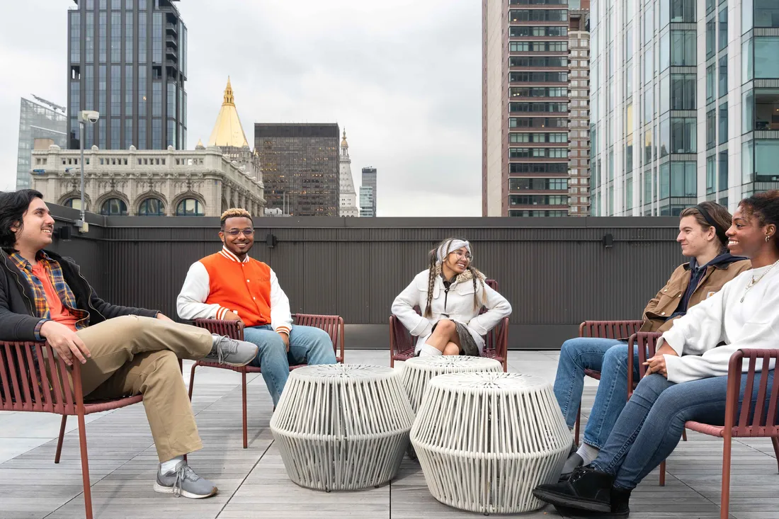 Three students standing and smiling in New York City.