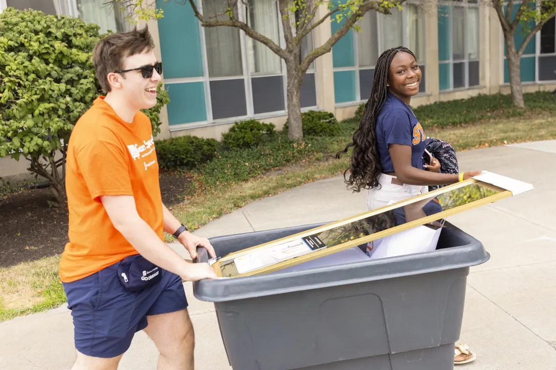 Goon Squad member pushing a cart for a student during move in.