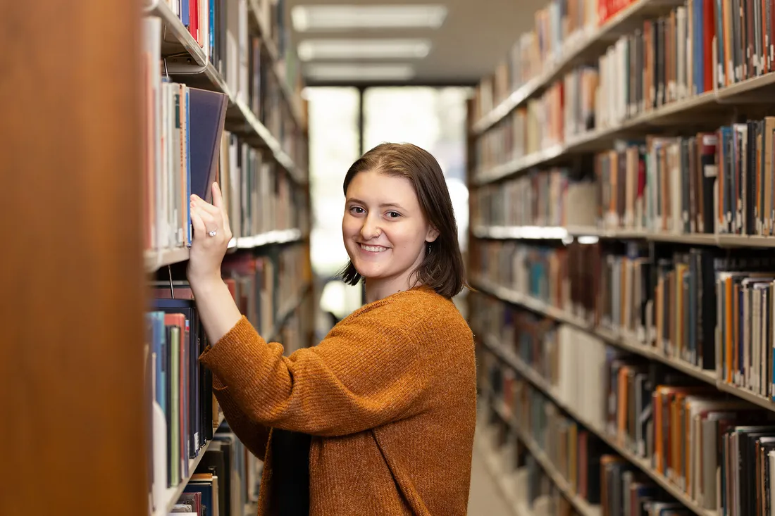 Person putting book on shelf.