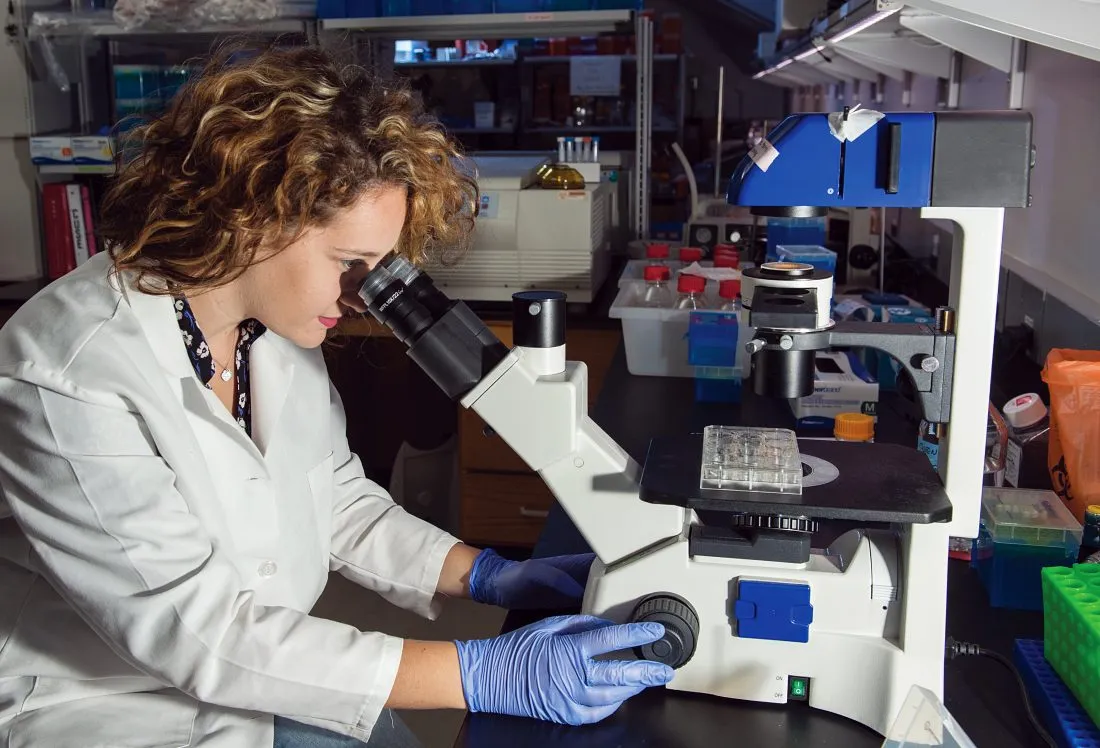 Sarah Moore looking into a microscope in a bioengineering lab