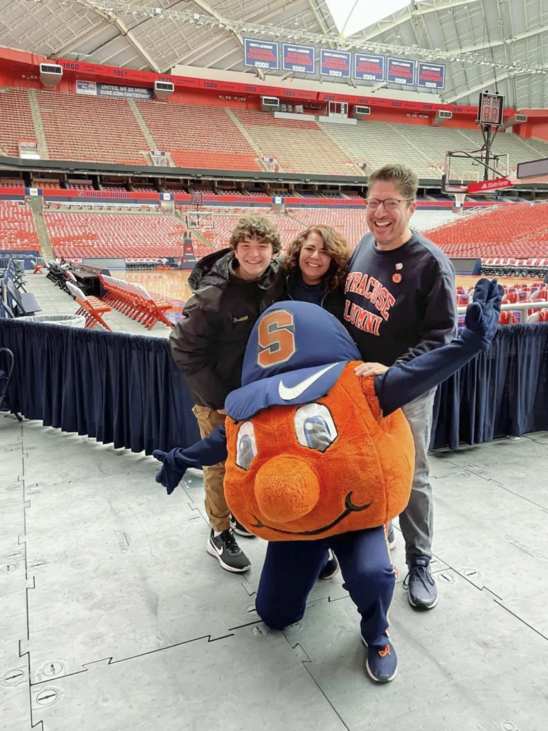 Otto the Orange posing with Mitch Messinger ’92, G’93 and his family inside the JMA Wireless Dome.