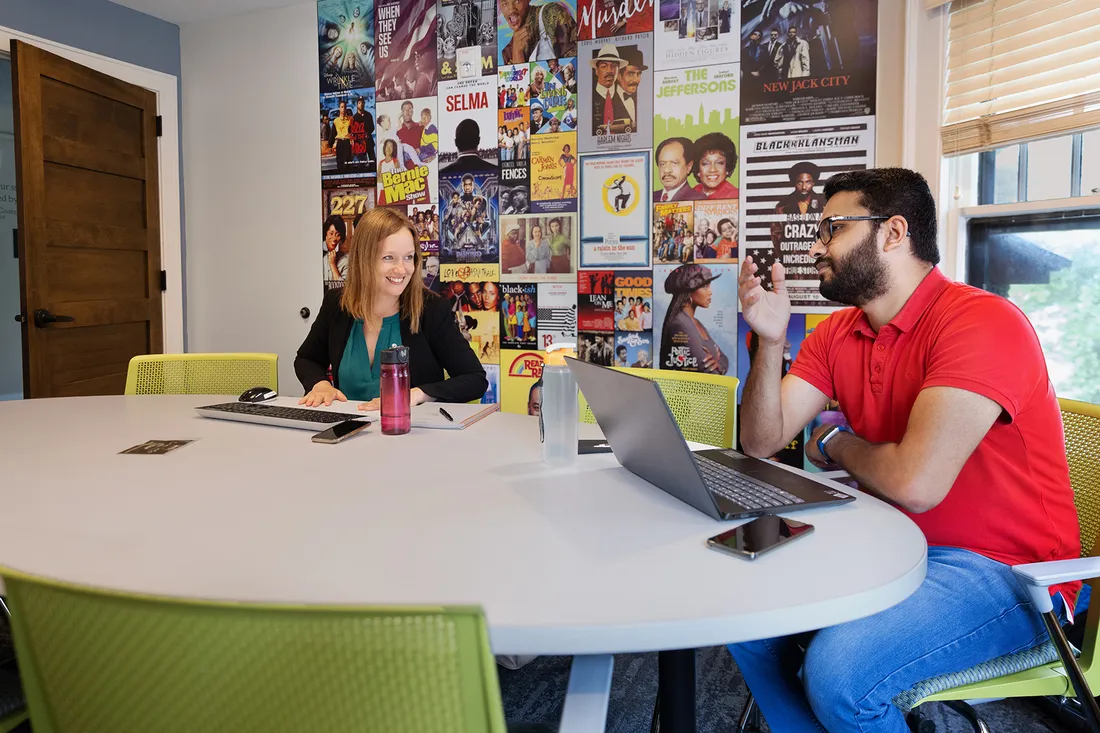 Nicole Fonger sits with a student around a table in conversation.