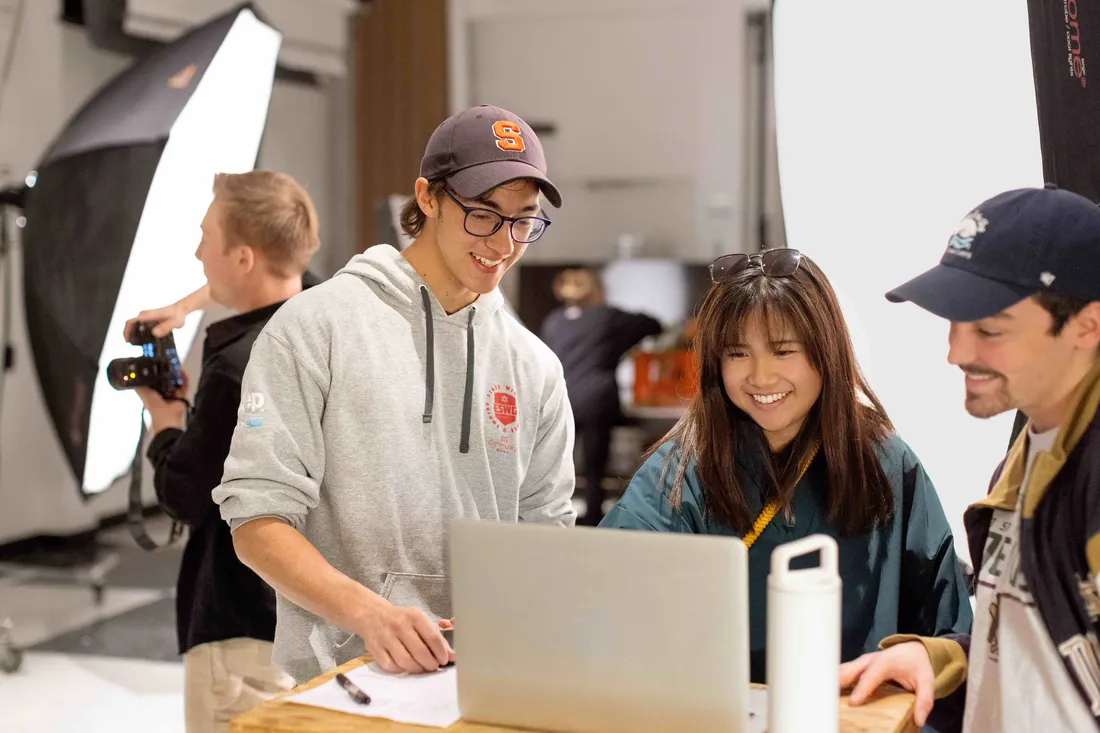 Students  looking at a computer and smiling.