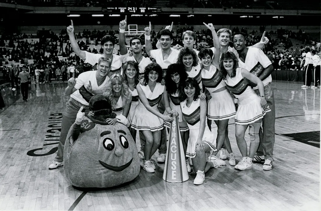 Vintage Otto the orange mascot standing inside with cheerleaders.