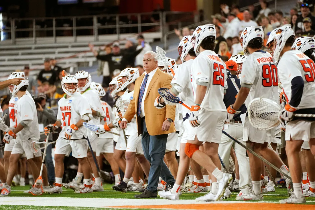 Gary Gait standing on a field with Syracuse University lacrosse players.