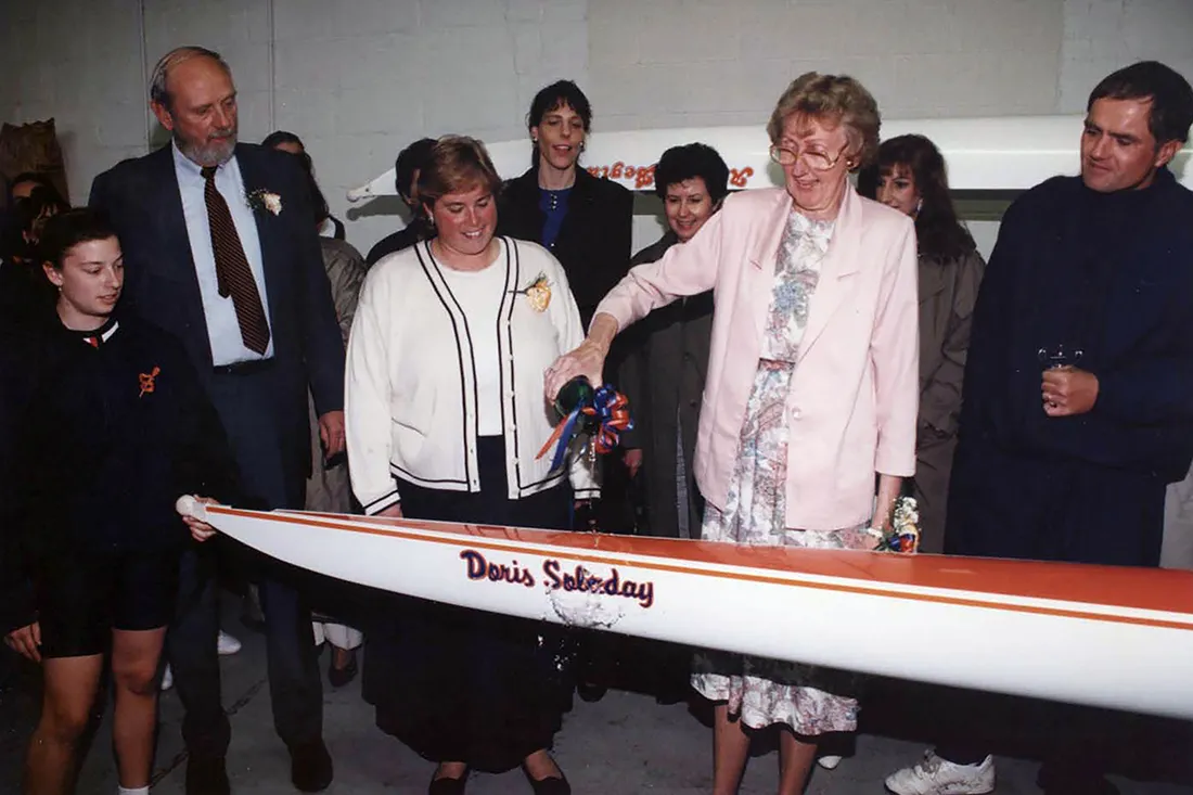 Woman cuts ribbon at rowing boat dedication.