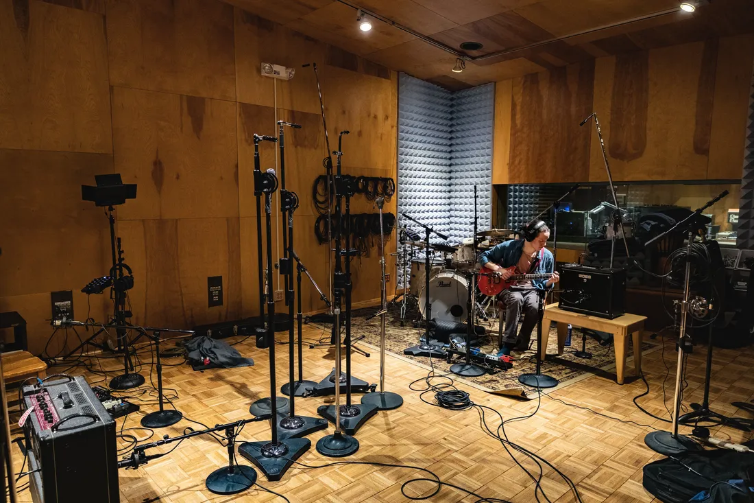 Student playing guitar in recording studio.