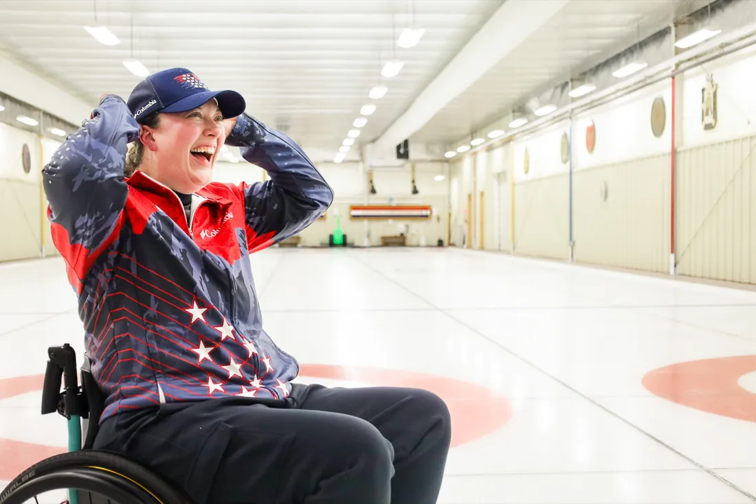 Katie (Boumans) Verderber L'16, smiling with her hands up on an ice rink.