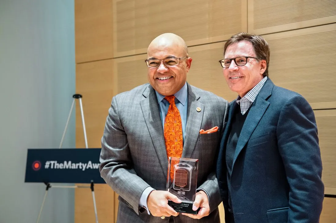 Mike Tirico and Bob Costas pose for a photo with Mike holding the Marty Glickman Award.
