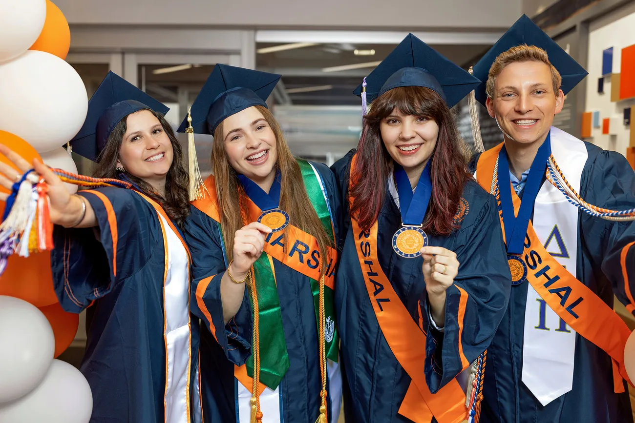 Student Marshals in their graduation robes holding medals.