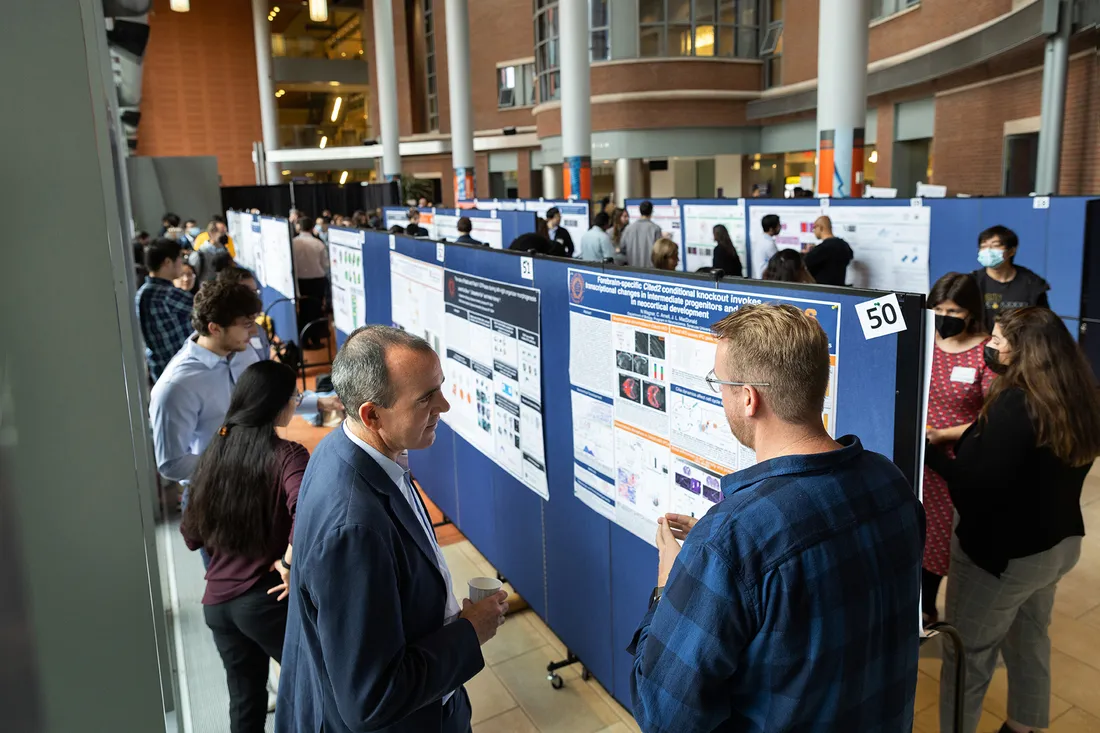 Students at exhibit showing research on boards.