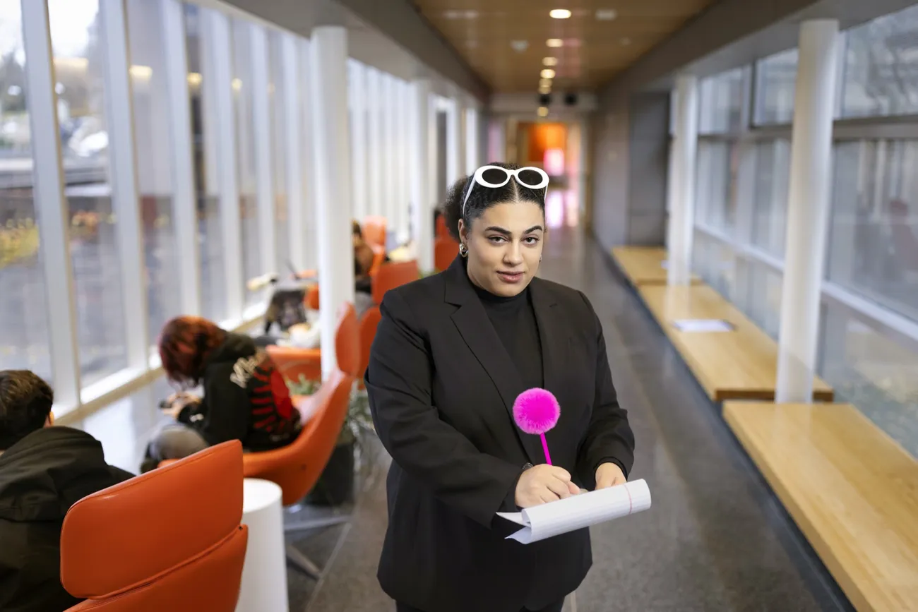 Carmella Boykin '21 posing in the hallway of the S.I. Newhouse School of Public Communications with her iconic pink pen, famously used in her Washington Post TikTok videos.