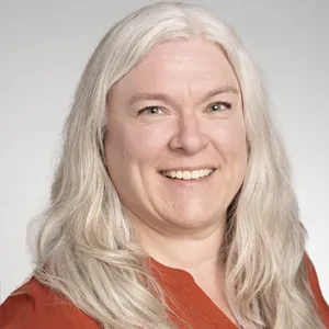 Cathy Mulholland in a orange shirt smiling.