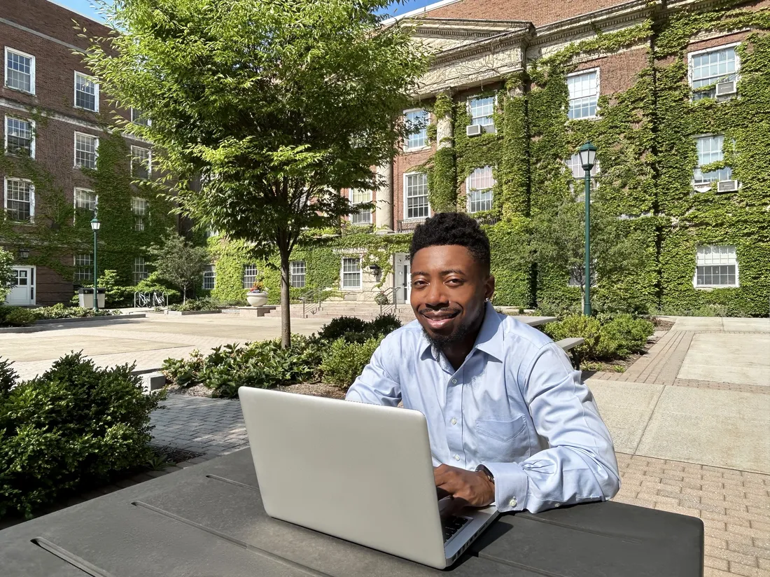 Aarick Knighton works on laptop in courtyard.