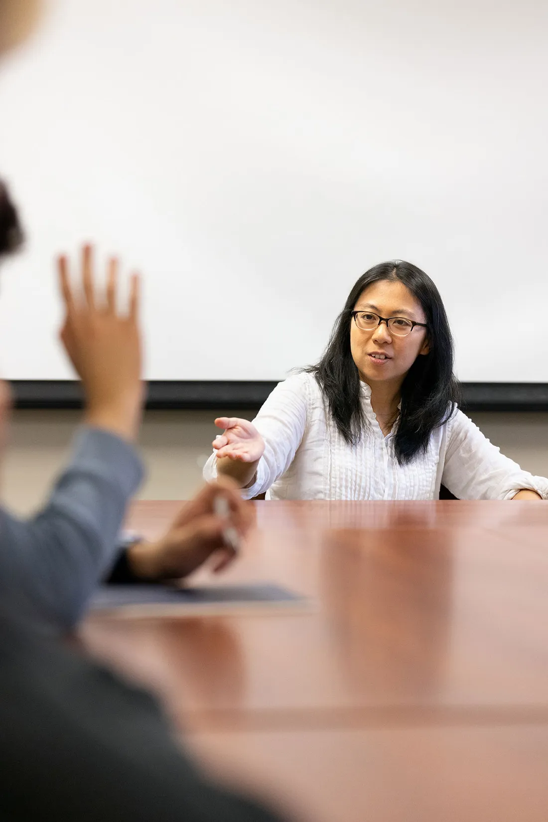 Professor sits at heads of table speaking with participants.
