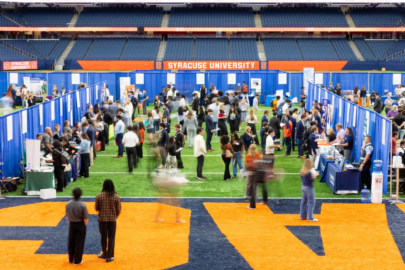 People walking around a Syracuse University Career Fair in the JMA Wireless Dome.