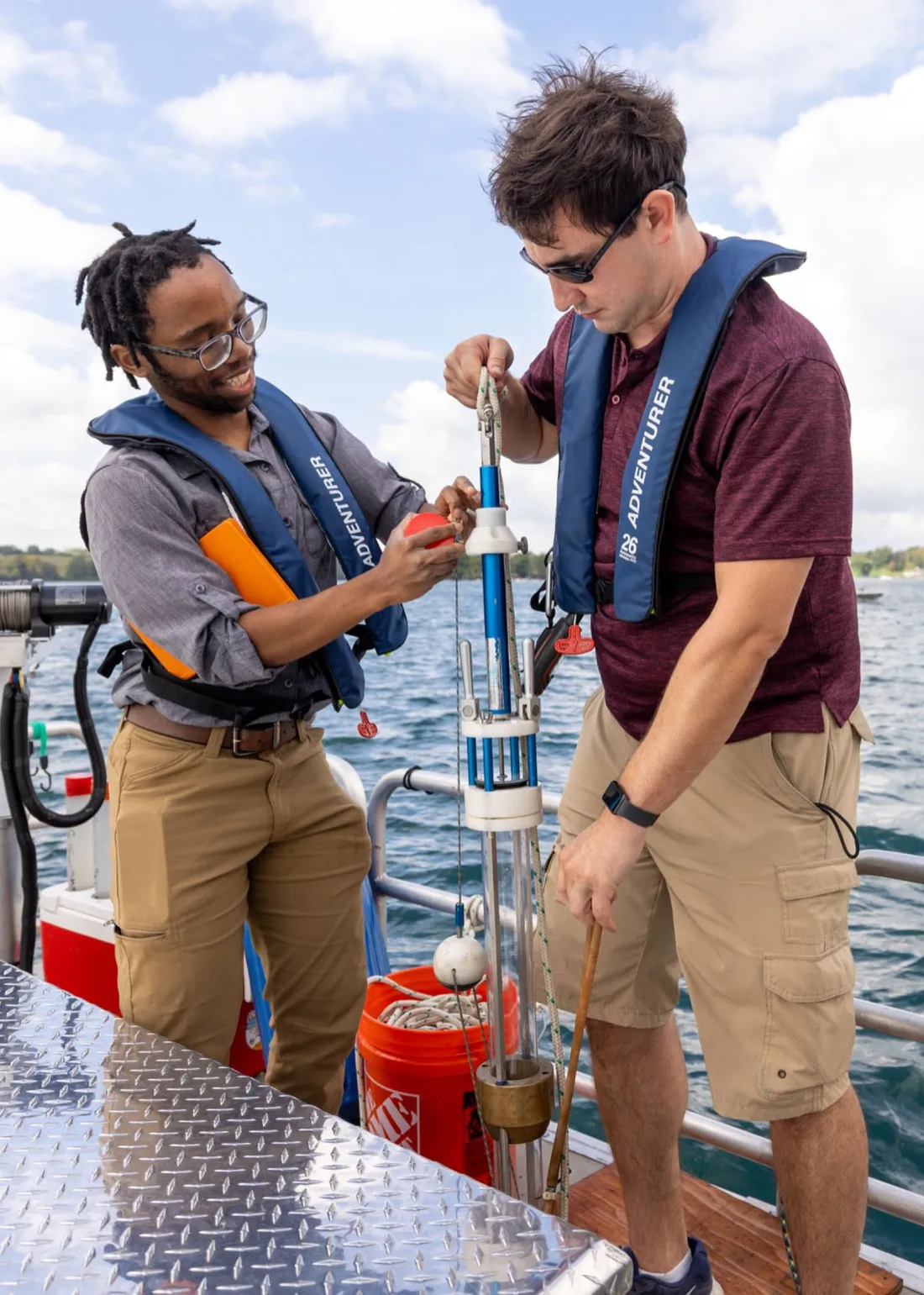 Two students hold a piece of sonar technology on a dock at Skaneateles Lake.