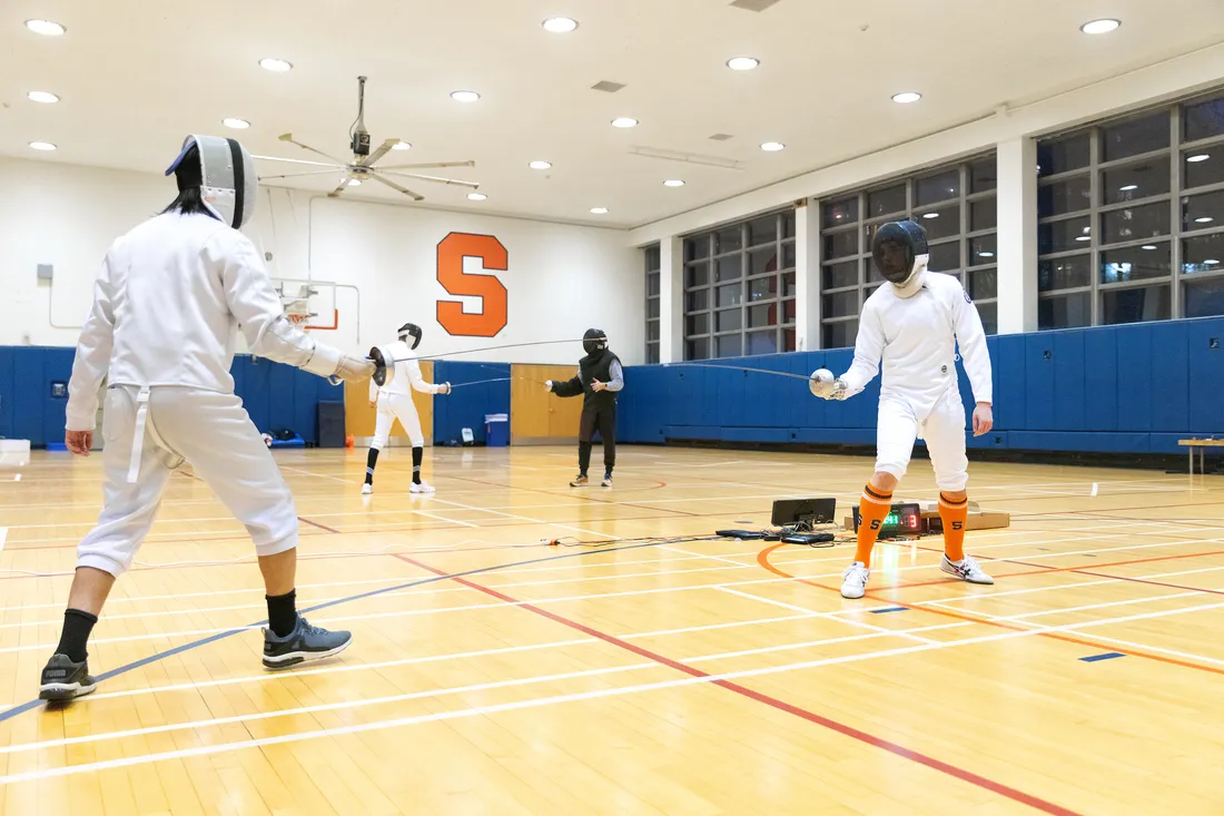 People fencing each other in a Syracuse University gym.