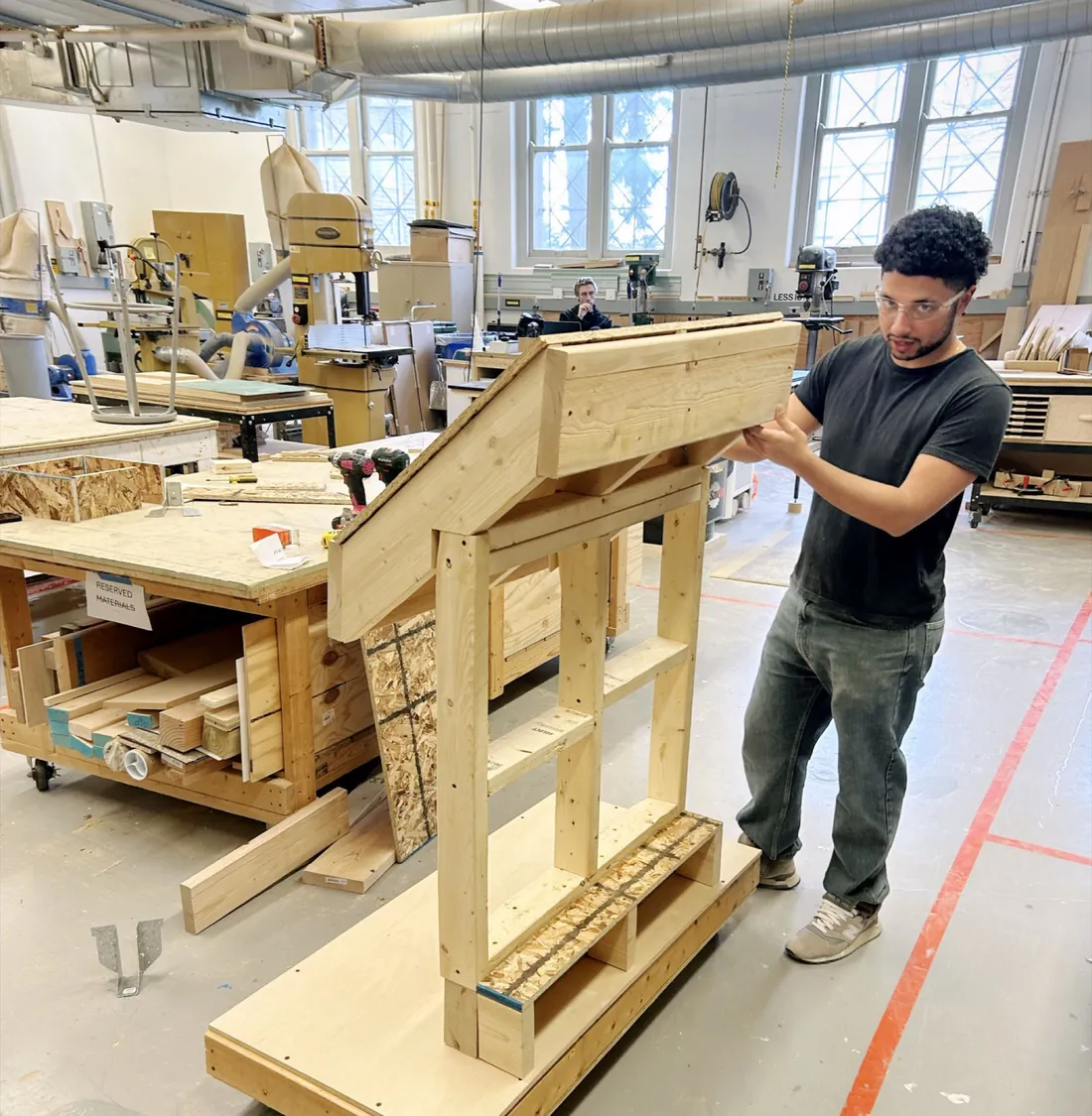Alumnus Kristian Nunez working on a prototype made of wood inside of a wood shop.