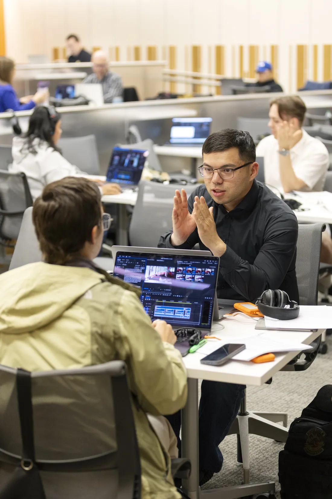 Two military students sitting and speaking to one another about a multimedia project.