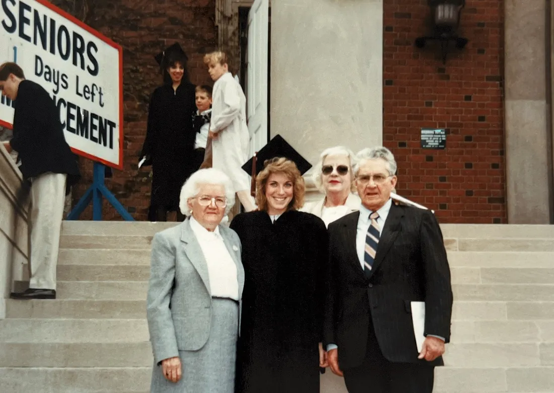 People standing with a graduate after in their cap and gown on Syracuse University's campus.
