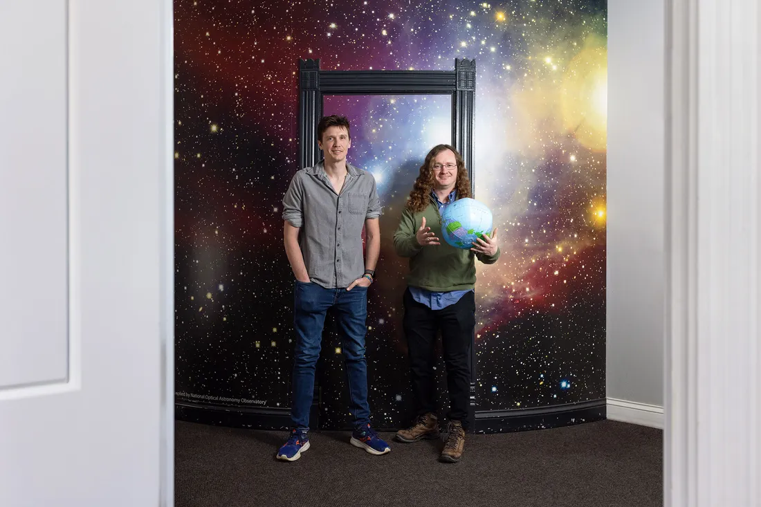 Two people standing holding a globe.