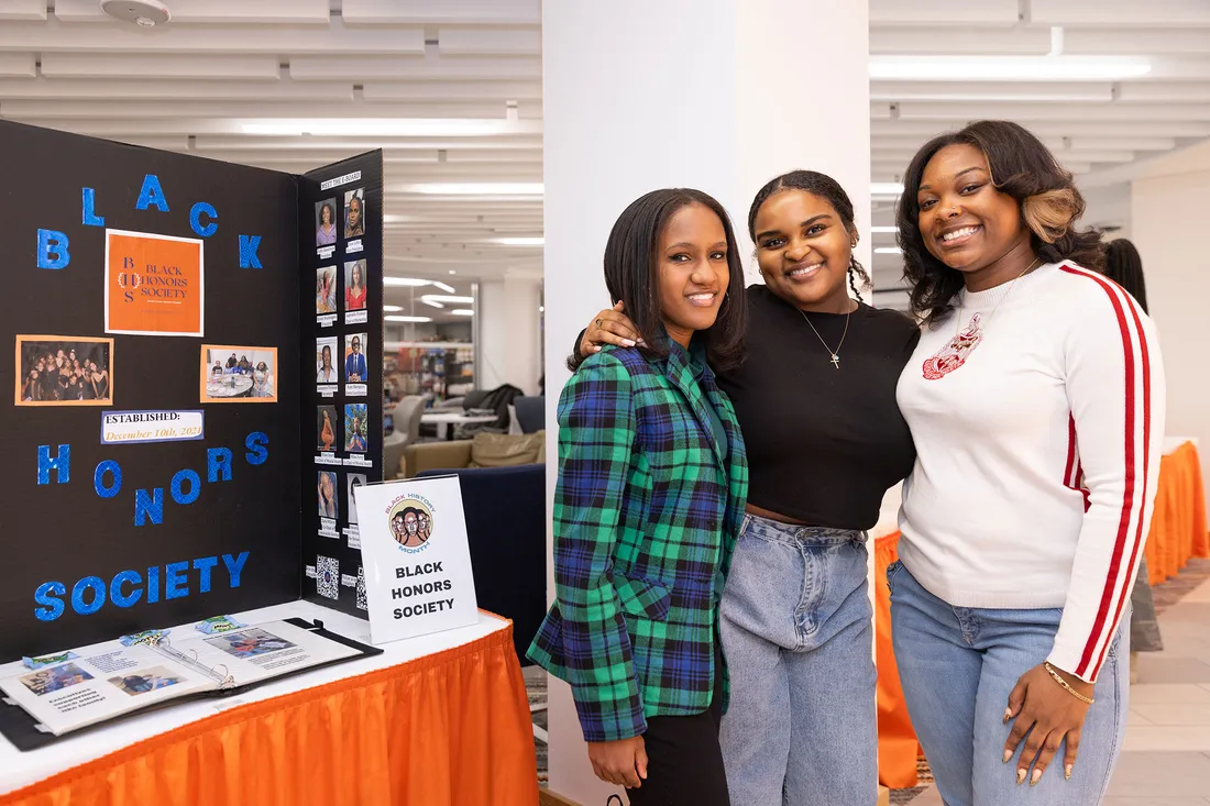 Three people posing together at an information fair.