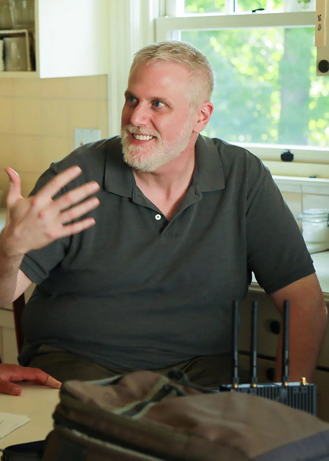 Gabe Honig speaking to a friend and sitting in a chair.