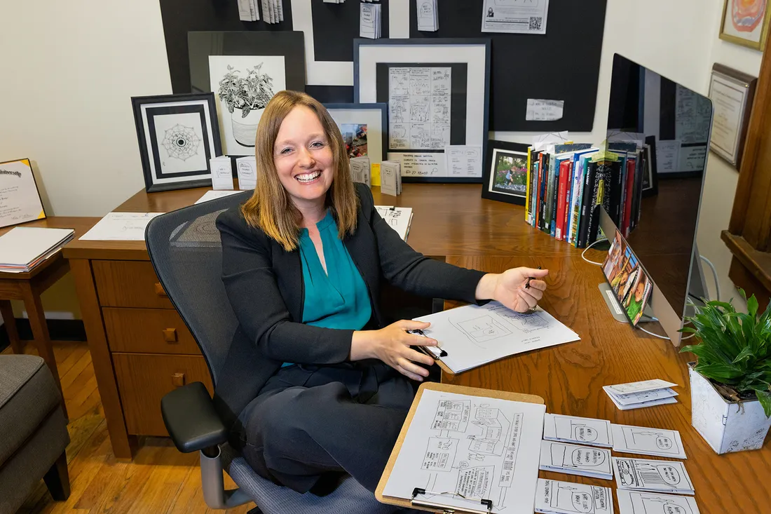 Portrait of Nicole Fonger, sitting at her desk smiling.