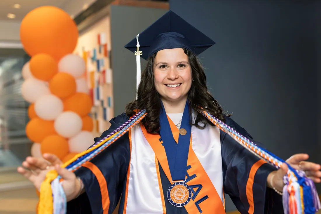 Ellen Cark in her commencement regalia holding her cords.