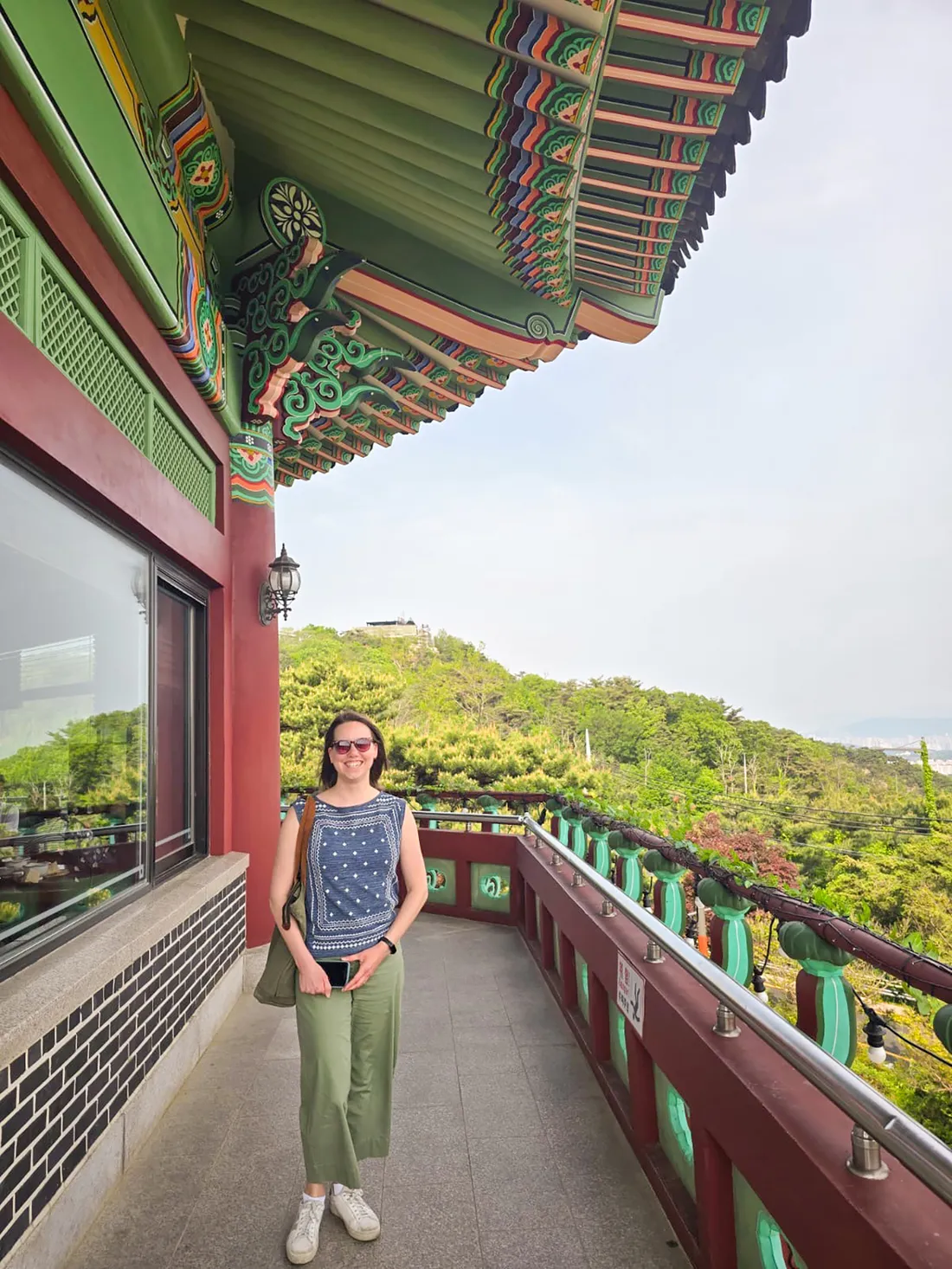 Person standing on balcony with trees in the background