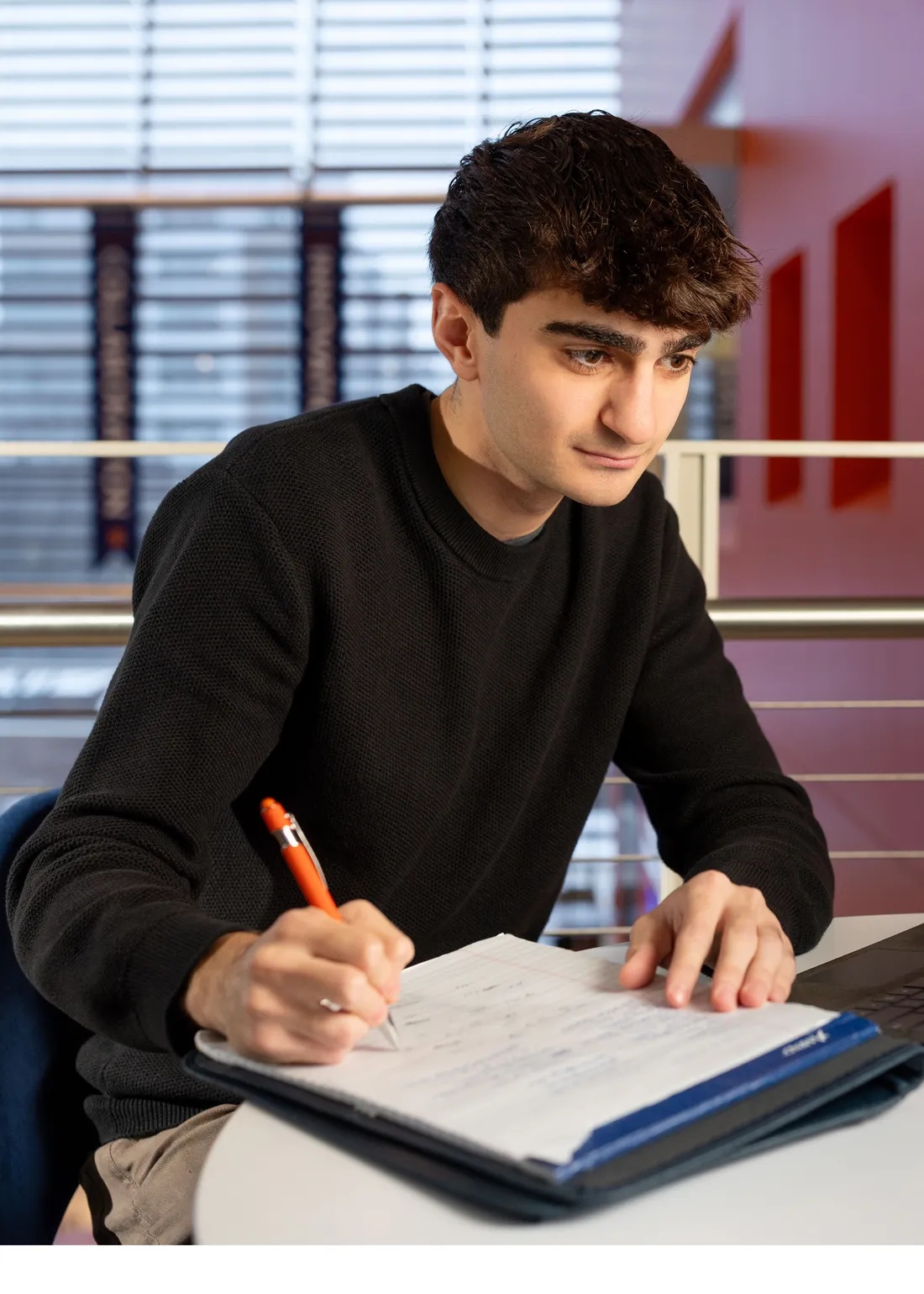 John Markarian sitting at a table and writing on a piece of white paper.