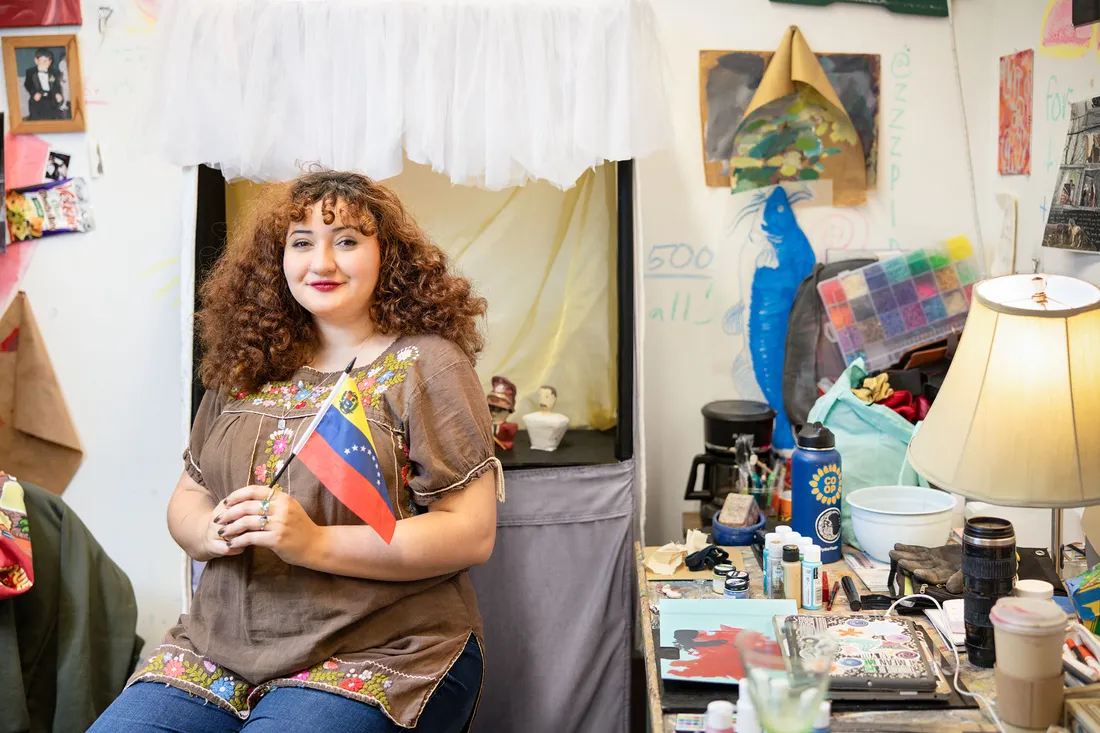 Student holding a flag surrounded by her artwork